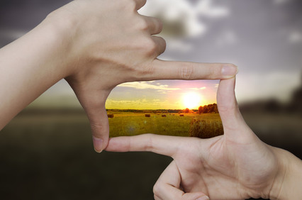 two fingers forming a frame with sunlight in the distance